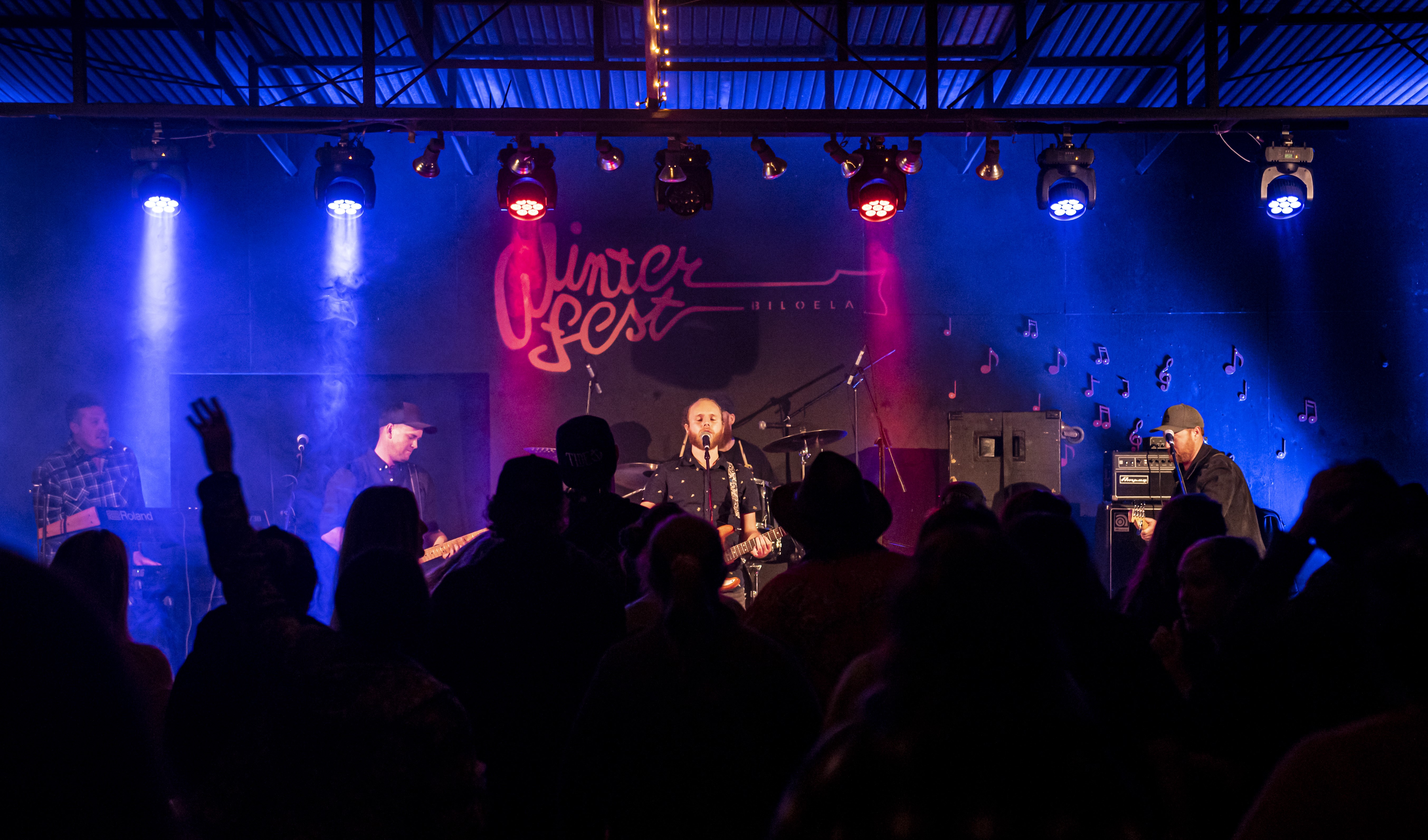A crowd looks toward a stage while the band plays
